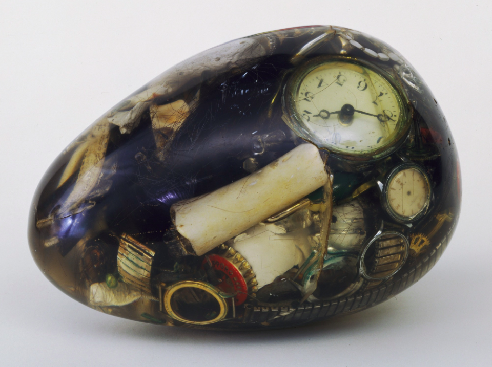 Compact Object by Natsuyuki Nakanishi, 1962. [A transparent egg filled with junk: old watch faces, a cigarette butt, bottle caps, crumpled papers.]