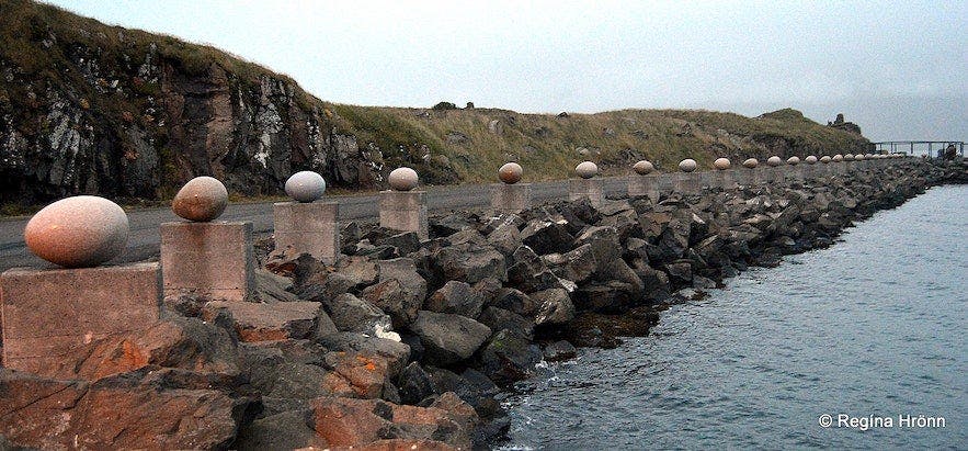 Eggin í Gleðivík (The Eggs of Merry Bay) by Sigurður Guðmundsson, 2009. [A wide shot of 34 large granite eggs set on plinths lining a road on one side and the ocean on the other.]