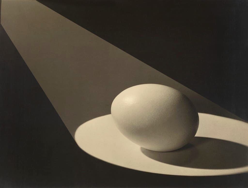 Egg in Spotlight by Paul Outerbridge, 1943. [A single egg with a literal spotlight on it, a shadow protruding behind.] 